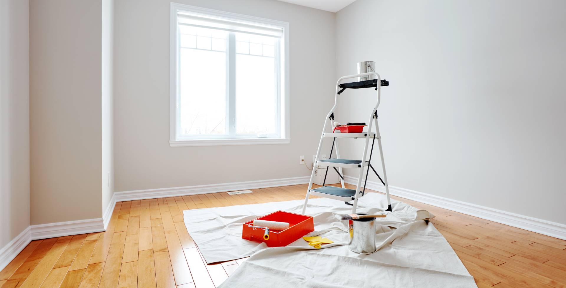 Habitación blanca con una escalera y herramientas de pintura